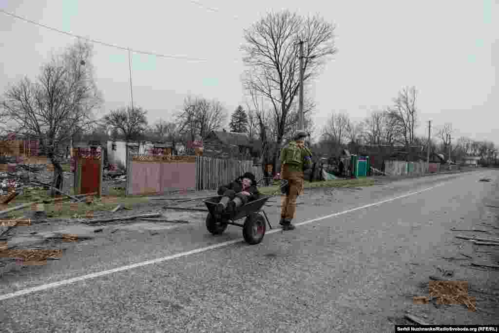 Военные и журналисты уговорили местного жителя Валентина эвакуироваться в безопасное место, март 2022 года / Справа: та же улица, март 2024 года. Валентин любил петь, он это делал и во время эвакуации. После освобождения Киевщины дедушку нашел и забрал его пасынок. Дед Валентин умер в окружении своих близких. Его дом уцелел, сейчас его ремонтируют. Военный Никита Шандиба продолжает служить в ВСУ