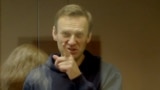 RUSSIA -- Russian opposition leader Aleksei Navalny, charged with defaming a World War II veteran, gestures from inside a glass cell during a court hearing in Moscow, February 16, 2021